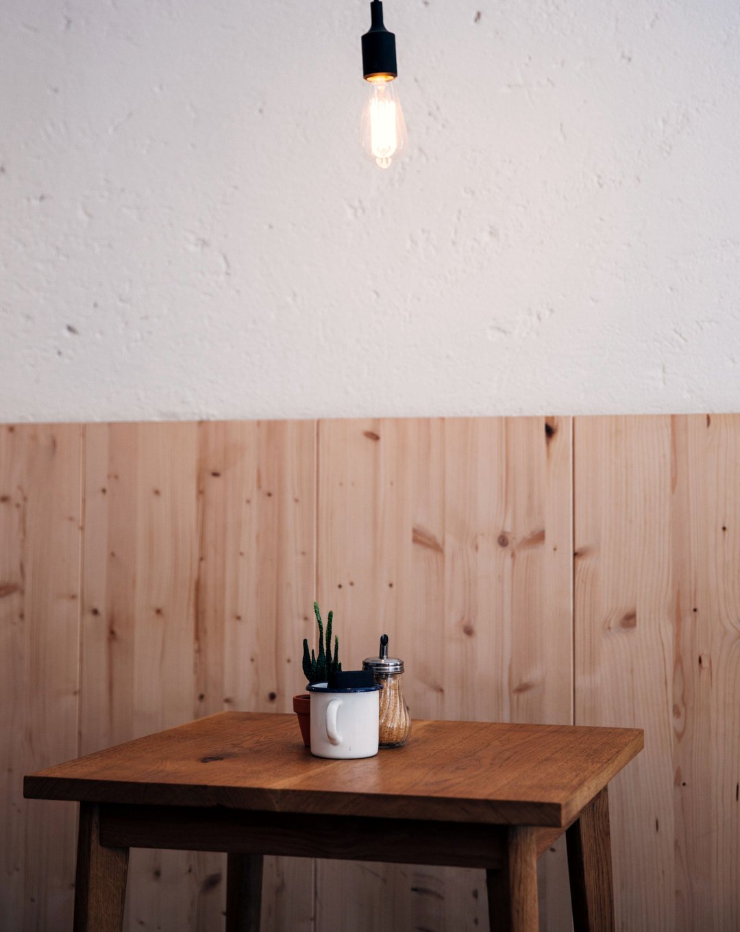Leerer Holztisch mit Glühlampe vor der Holzvertäfelung