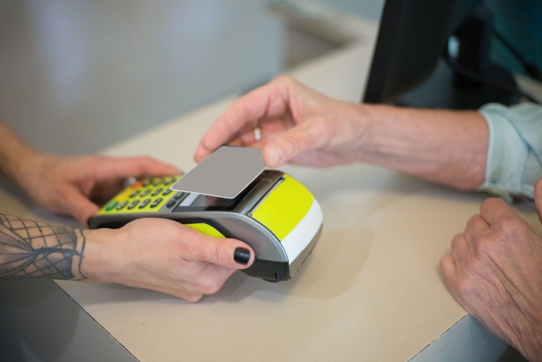 Am Tresen hält eine Kundin ihre Karte an das Kartenlesegerät, das die Friseurin ihr hinhält