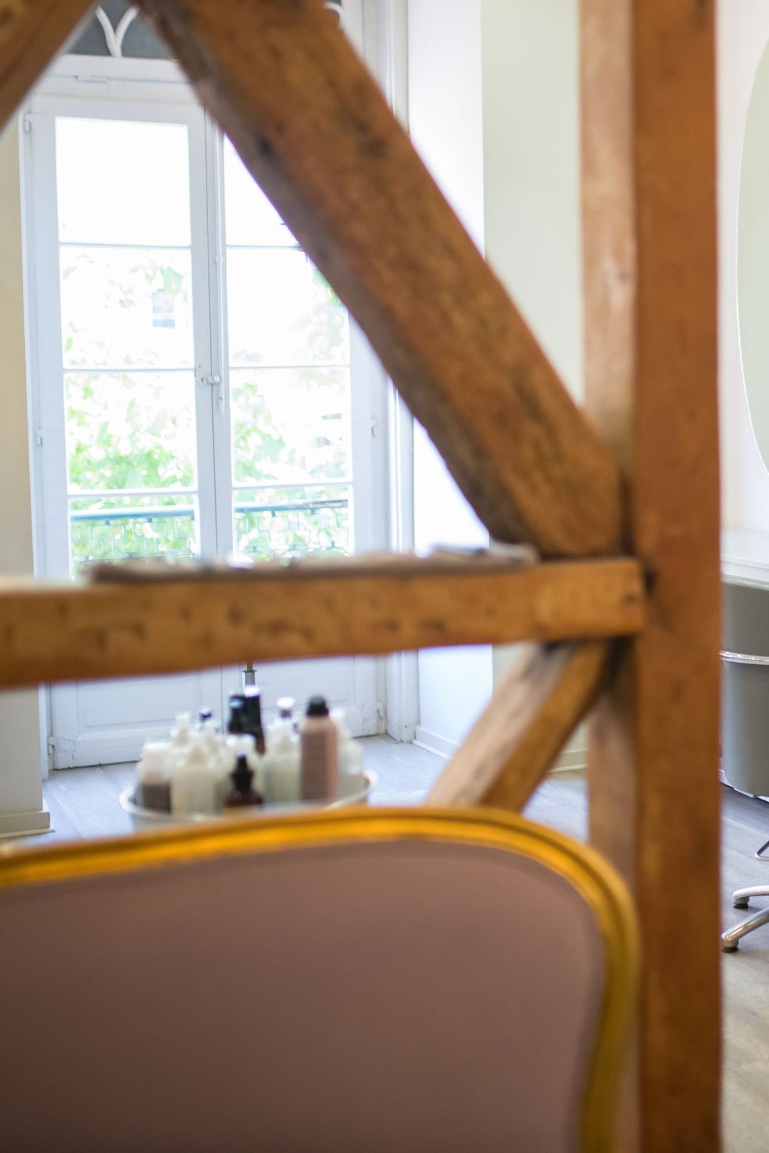 Eine Friseurin frisiert einer Kundin am hellen Fenster das graue Haar