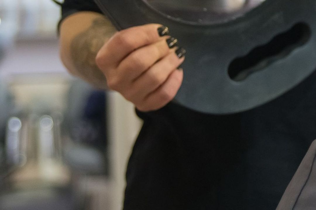 Hinter einer Kundin hält die Friseurin einen ovalen Handspiegel, damit sie ihren Hinterkopf sieht