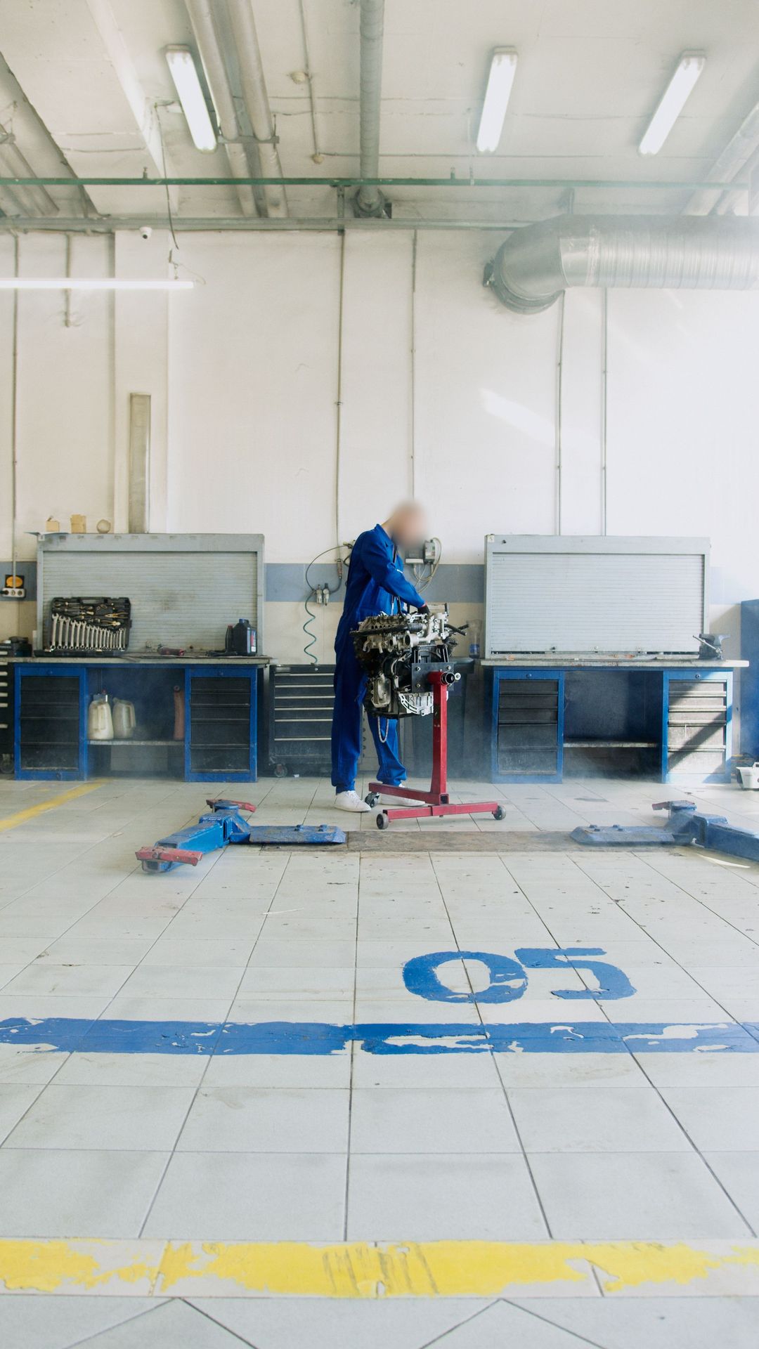 Die helle Halle mit blauen Werkbänken, auf dem Boden die Nummer 05 der Hebebühne